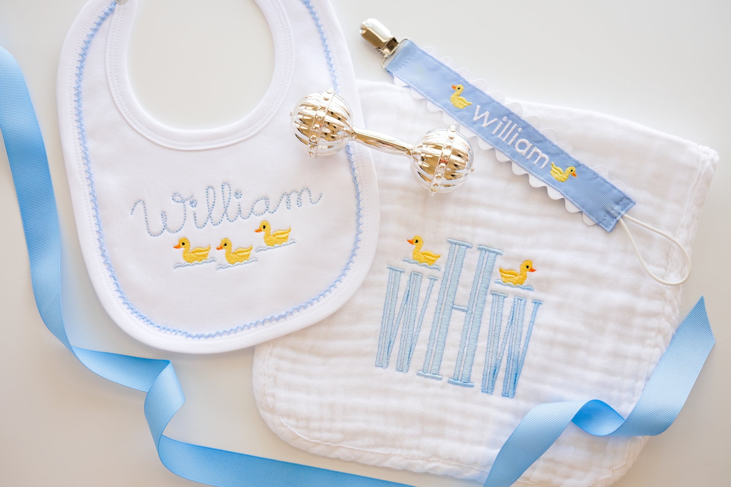 Baby bib, burp cloth, and rattle set with 'William' embroidery on a white background